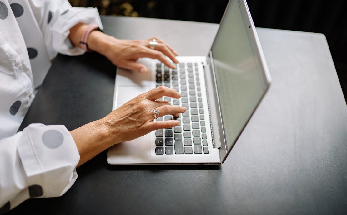 Close-up shot of woman typing on a laptop keyboard