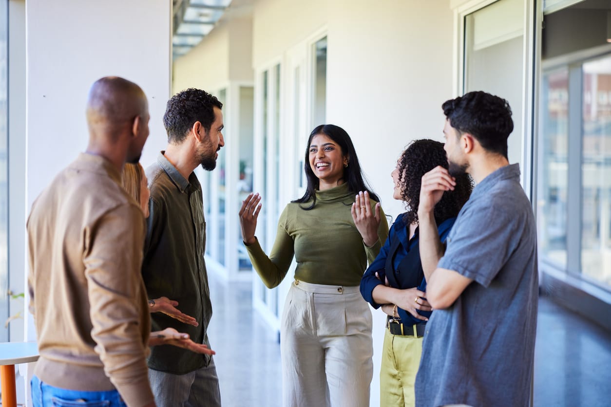 Laughing young businesswoman talking with colleagues in an office hallway