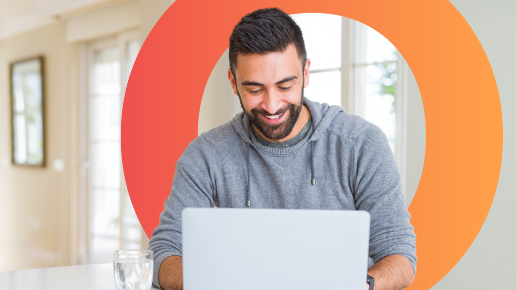 Man sat in his house, smiling at an open laptop