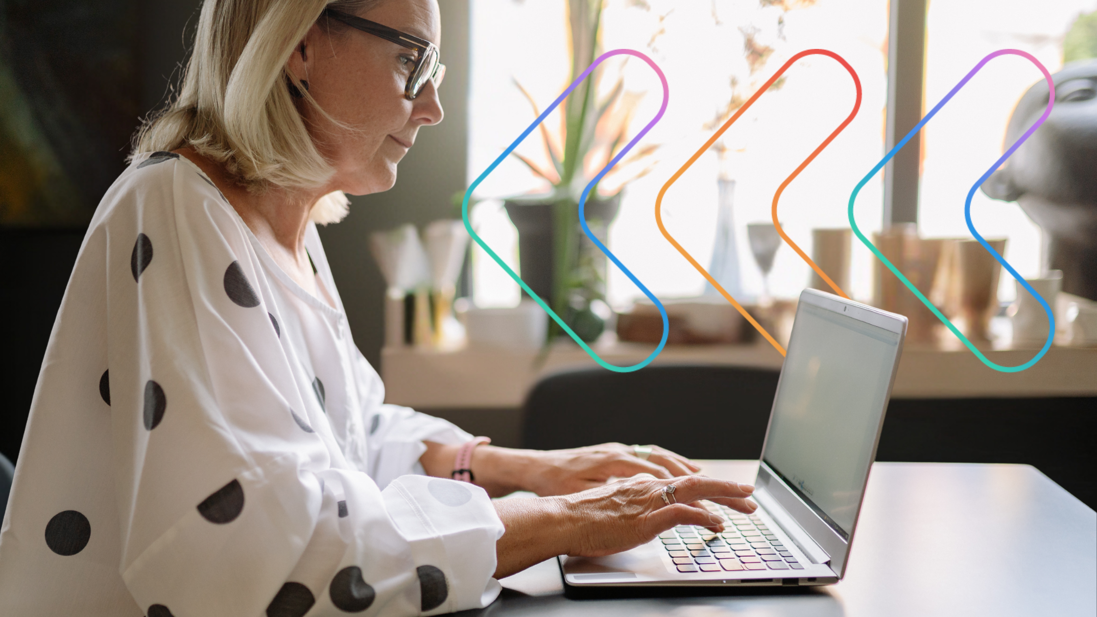 Side shot of woman sat a desk, typing on a laptop