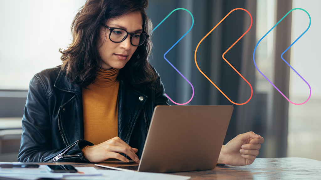 Woman sat at a desk, looking at a laptop thoughtfully